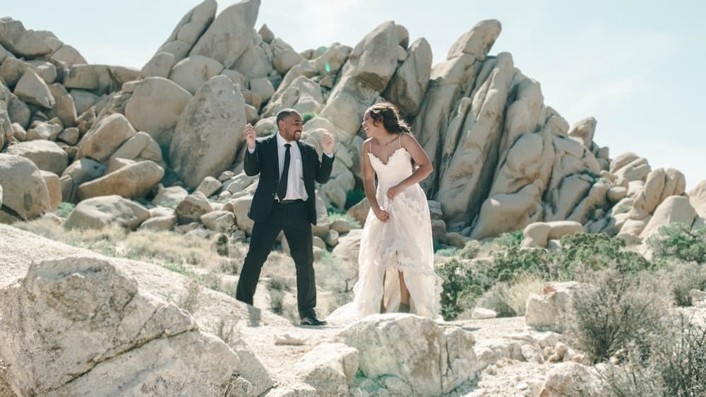 Newlyweds standing on dramatic rock formations