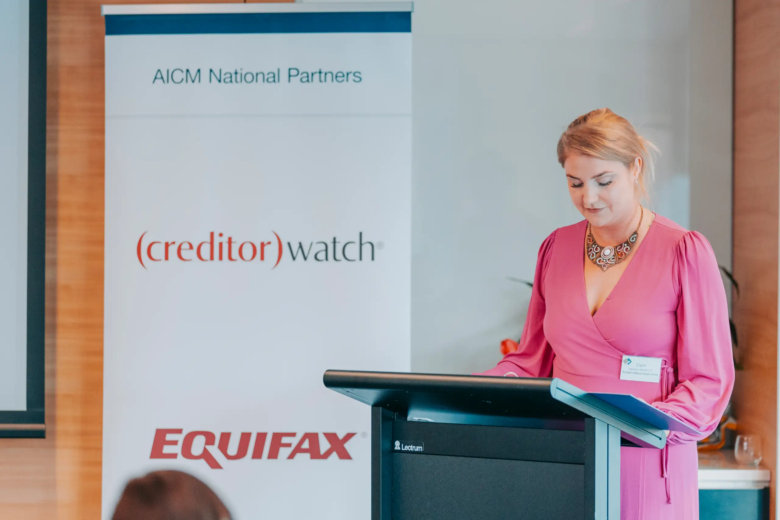 Speaker at the lectern beside an AICM National Partners banner at a corporate event in Adelaide
