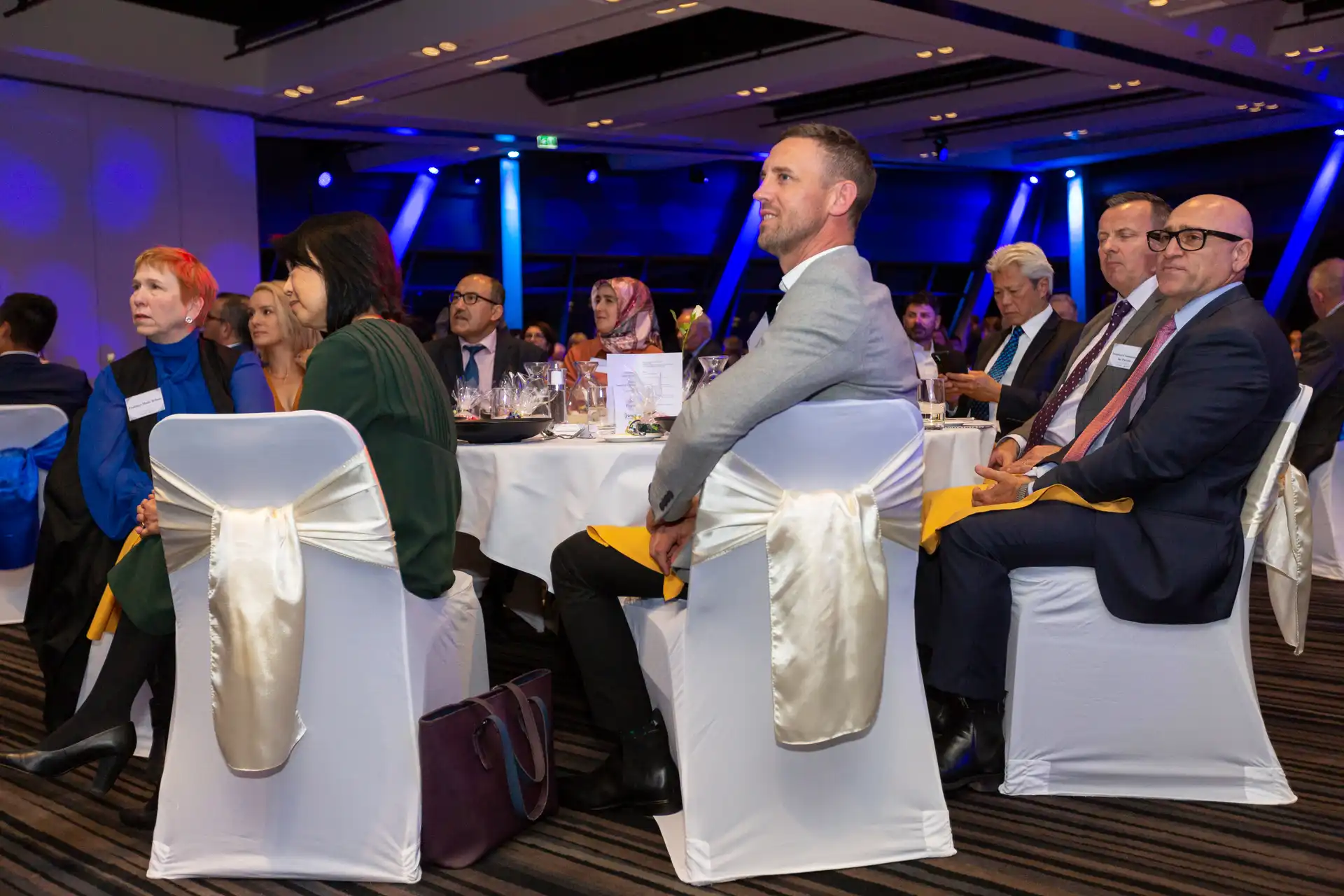 Delegates seated at round banquet tables listening to a conference session